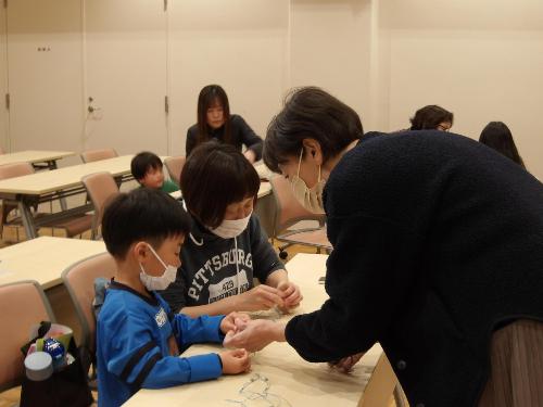 ビーズのネックレスの作り方を講師から教えてもらう様子